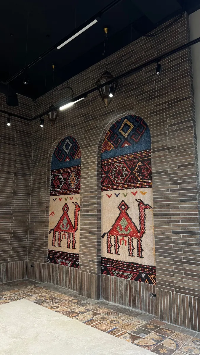Панно с верблюдами в нарисованных арках на стене кафе